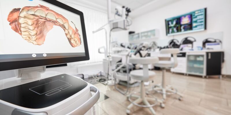 Snapshot of empty clean dental office. Interior of modern dental clinic. Computer screen with high precision digital jaw print on it on foreground.