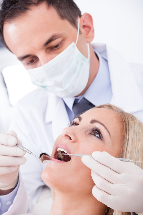 Male Dentist Examining Female Patient In Clinic