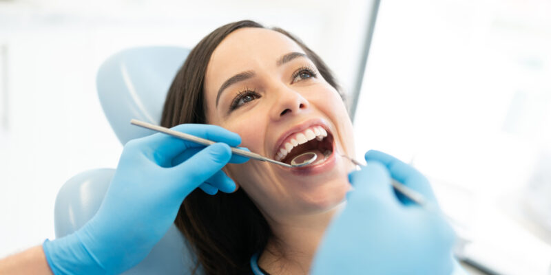 Closeup of dentist examining patient with mirror and carver at clinic