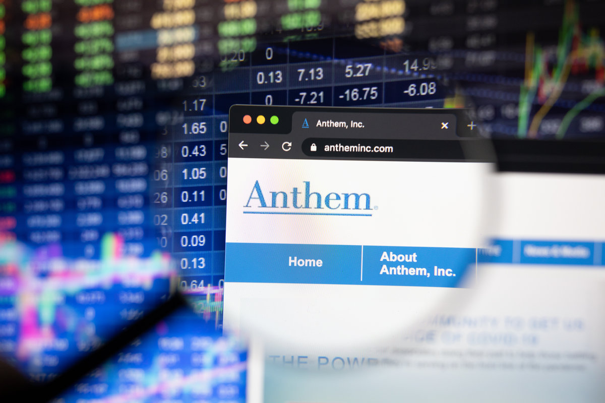 Anthem company logo on a website with blurry stock market developments in the background, seen on a computer screen through a magnifying glass