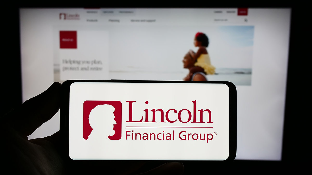 Stuttgart, Germany - 08-02-2023: Person holding smartphone with logo of US financial company Lincoln National Corporation on screen in front of website. Focus on phone display.