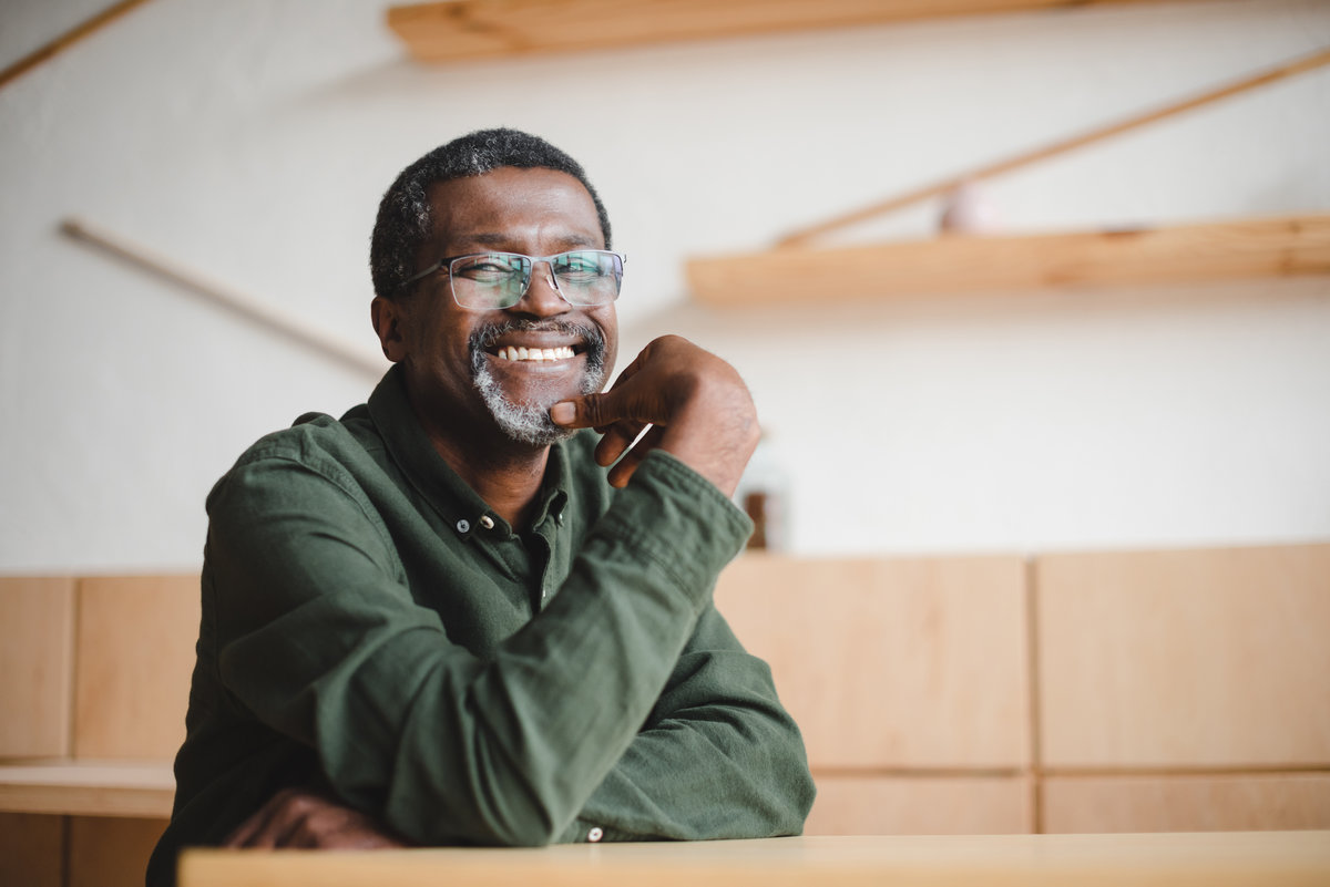 happy mature african american man sitting in cafe and looking at camera
