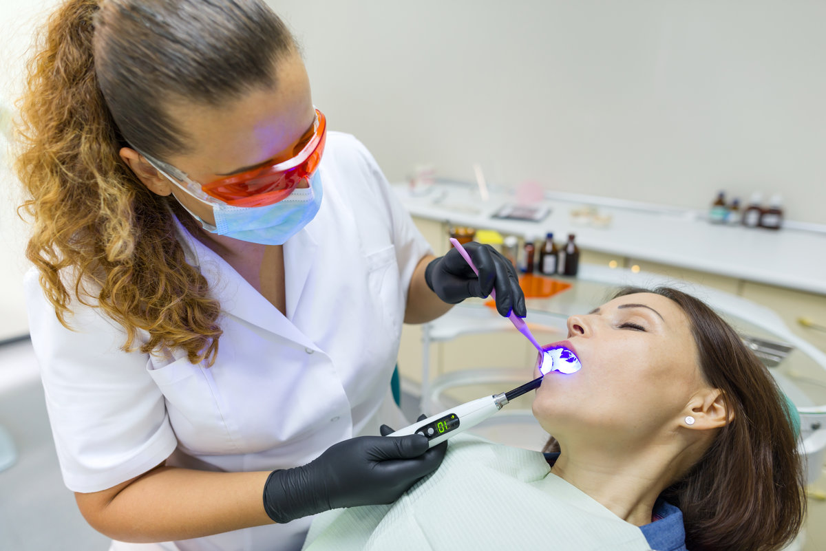 Adult female dentist treating patient woman teeth. Medicine, dentistry and healthcare concept.