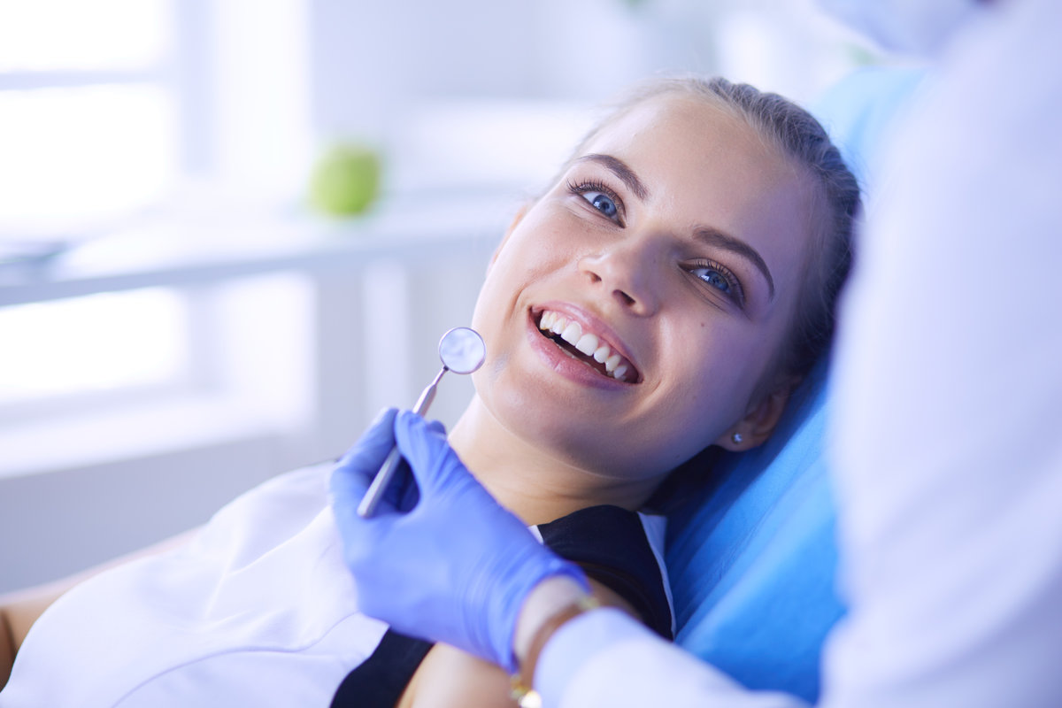 Young Female patient with pretty smile examining dental inspection at dentist office