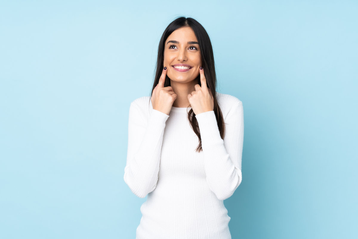 Young caucasian woman isolated on blue background smiling with a happy and pleasant expression