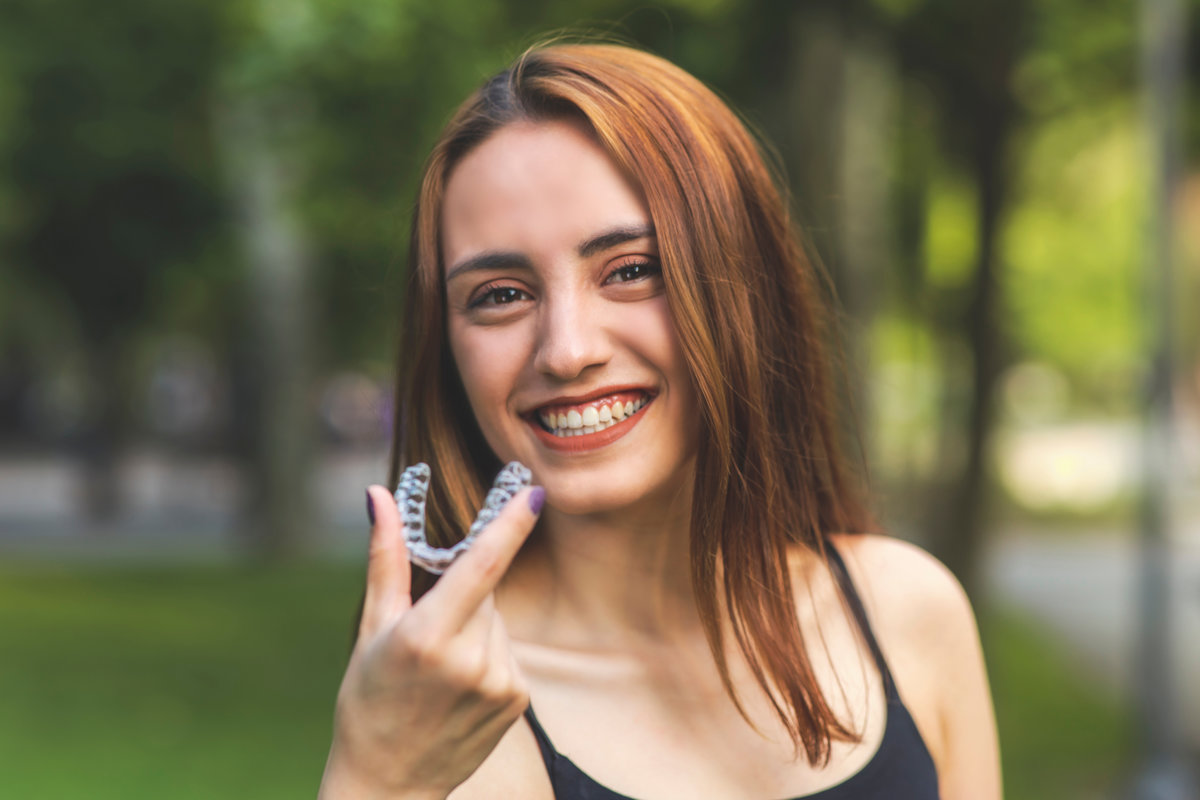 Beautiful smiling Turkish woman is holding an invisalign bracer with vibrant colors