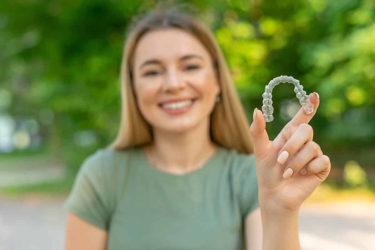 Beautiful smiling woman is holding an invisalign bracer