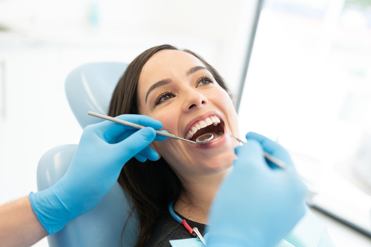 Closeup of dentist examining patient with mirror and carver at clinic