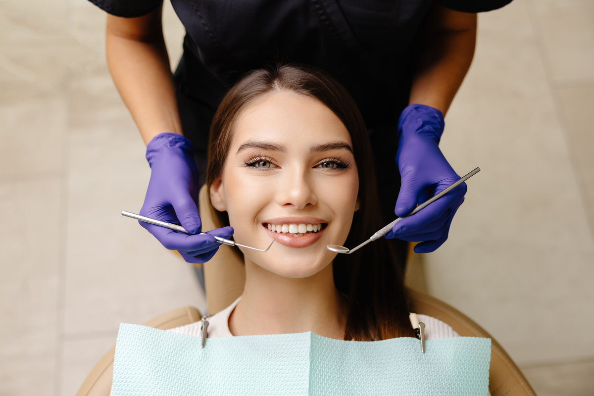 Happy patient during a visit to the dentist. The doctor is checking teeth using a dental instrument, ensuring proper oral care in the dentistry clinic.