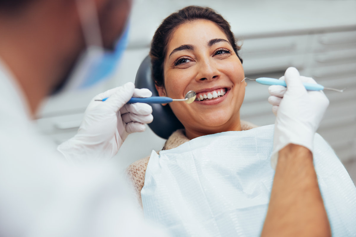 Over the shoulder view of a dental doctor treating female patient. Female having routine dental checkup at dentist.