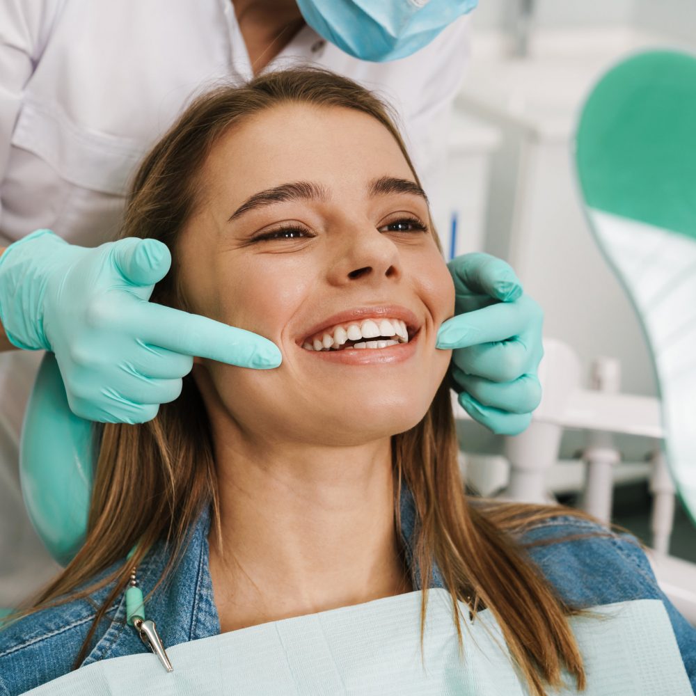 European young woman smiling while looking at mirror in dental clinic